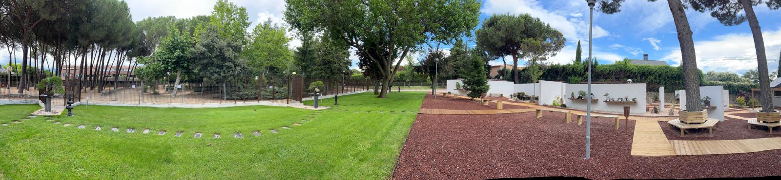 Fotografía panorámica de la entrada principal al Museo Municipal del Bonsái en Collado Villalba, mostrando la integración del vallado de acero corten y mampostería con el arbolado preexistente