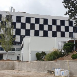 Vista exterior de la Clínica López Ibor mostrando el patrón geométrico de damero blanco y negro en la fachada, durante la rehabilitación