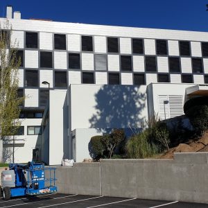 Resultado final de la rehabilitación de la fachada en damero de la Clínica López Ibor con el entorno de aparcamiento