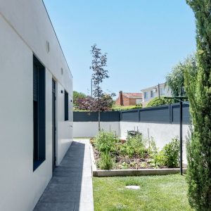 Vista del pasillo lateral y huerto urbano en bancal de madera en el jardín de una vivienda unifamiliar de obra nueva en Madrid por Espacio Acorde