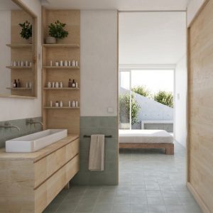 Perspectiva desde el baño suite hacia el dormitorio principal en ampliación de vivienda en Torrelodones, mostrando mueble lavabo y estantes de madera de abedul, zócalo de azulejo verde y cama de madera al fondo junto a ventanal con terraza exterior, por Espacio Acorde.