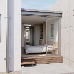Vista exterior de patio privado y acceso a dormitorio suite en ampliación en Torrelodones, con ventanal corredero con tarima de madera, muro de hormigón visto, mampostería de piedra y árbol caducifolio de hojas amarillas, por Espacio Acorde.