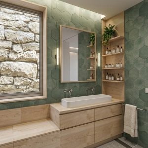 Vista panorámica del interior de un baño suite en ampliación en Torrelodones, con lavabo sobre mueble de abedul, zócalo de azulejo verde hexagonal, ventana con vistas a muro de piedra y paso abierto al dormitorio principal con ventanal exterior, por Espacio Acorde