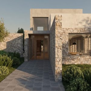 Fachada principal de vivienda unifamiliar con muros de mampostería en piedra natural, acceso en madera, ventanal a comedor y paisajismo en Madrid.