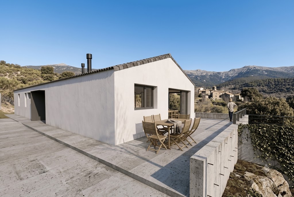Vivienda unifamiliar en la Sierra de Madrid con amplia terraza de hormigón, mobiliario exterior de madera y vistas al pueblo de montaña.