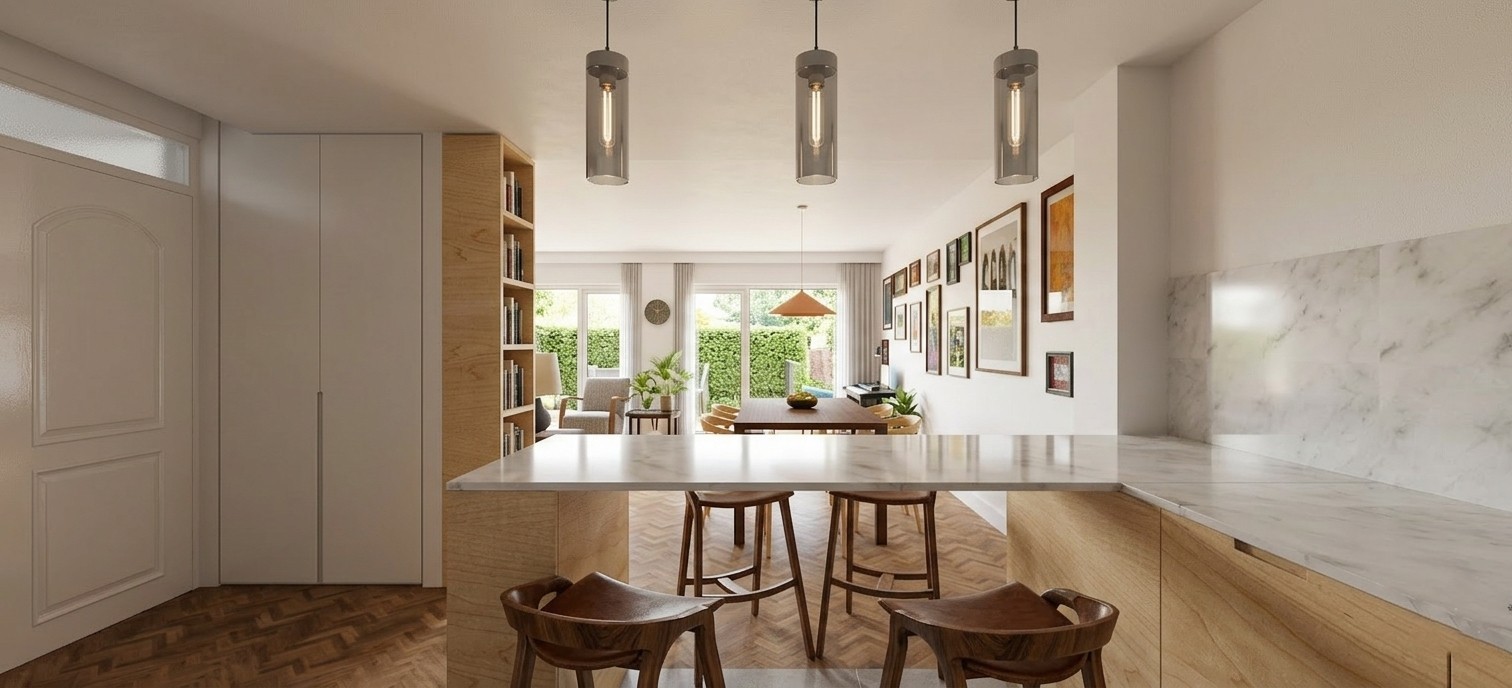 Vista desde la cocina hacia el salón-comedor tras la reforma integral de una vivienda en Alcalá Norte (Madrid), mostrando barra de mármol con taburetes de madera, luminarias cilíndricas suspendidas, suelo de espiga y salida al jardín ajardinado, por Espacio Acorde.