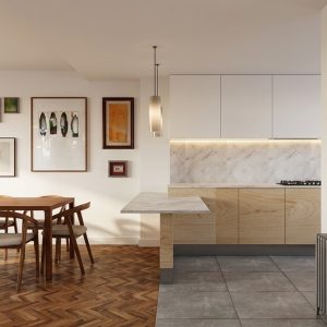 Vista frontal de la zona de comedor con mesa de madera y galería de cuadros en pared, junto a la cocina abierta con península de mármol, armarios superiores blancos y pavimento cerámico gris en vivienda de Alcalá Norte (Madrid), por Espacio Acorde.