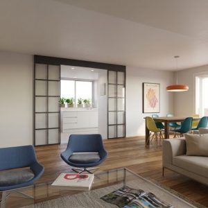 Perspectiva de salón con puerta corredera de vidrio y hierro que da acceso a cocina reformada en Madrid, con zona de comedor y suelo de madera, por Espacio Acorde.