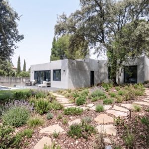 vivienda unifamiliar prefabricada de hormigón en Madrid, mostrando un camino de acceso de hormigón y puerta oscura diseñado por Espacio Acorde.