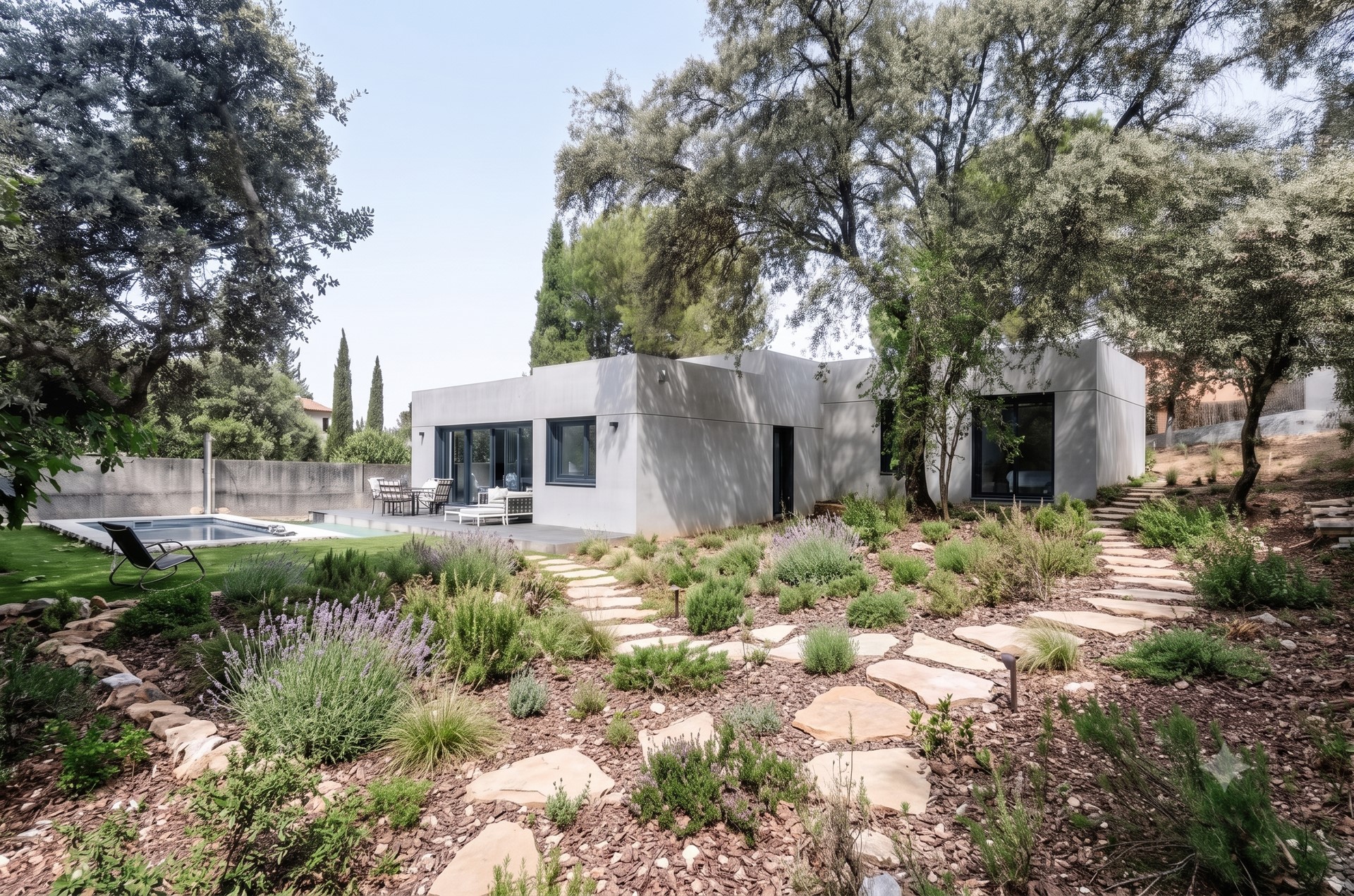 vivienda unifamiliar prefabricada de hormigón en Madrid, mostrando un camino de acceso de hormigón y puerta oscura diseñado por Espacio Acorde.